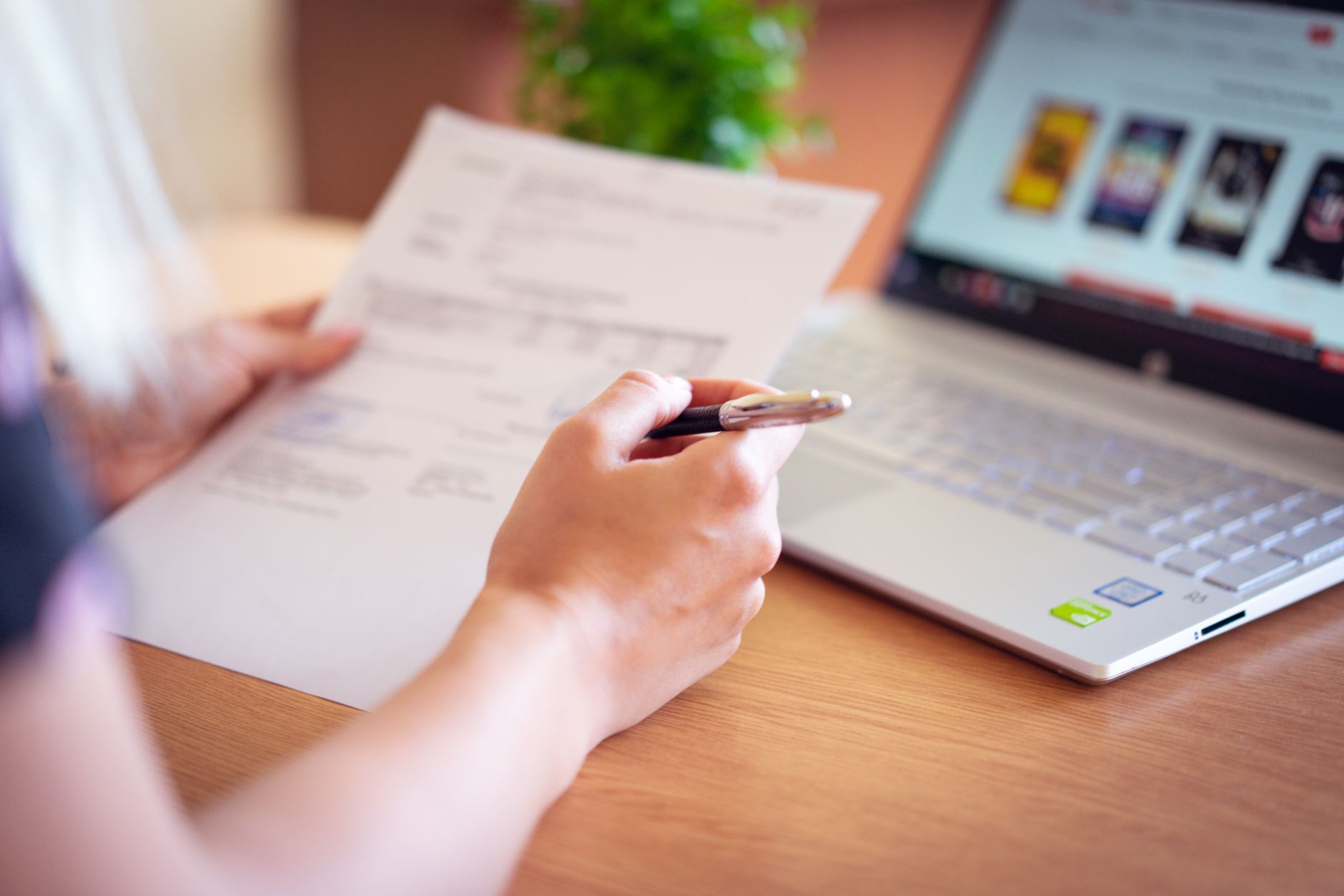 A person reviews an identity theft recovery checklist on a laptop at a kitchen table with printed letters nearby.