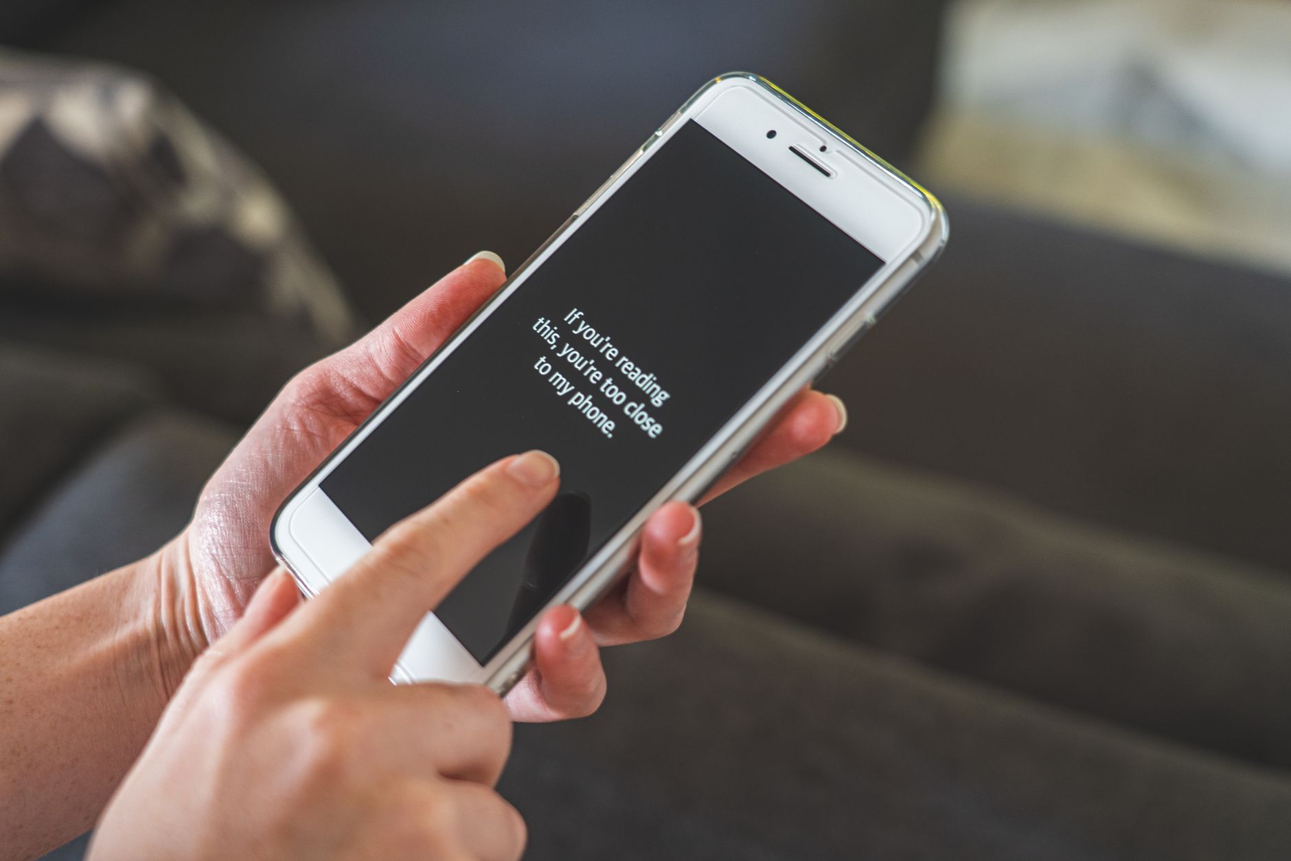 Hands hold a smartphone showing a suspicious text message warning about account access.