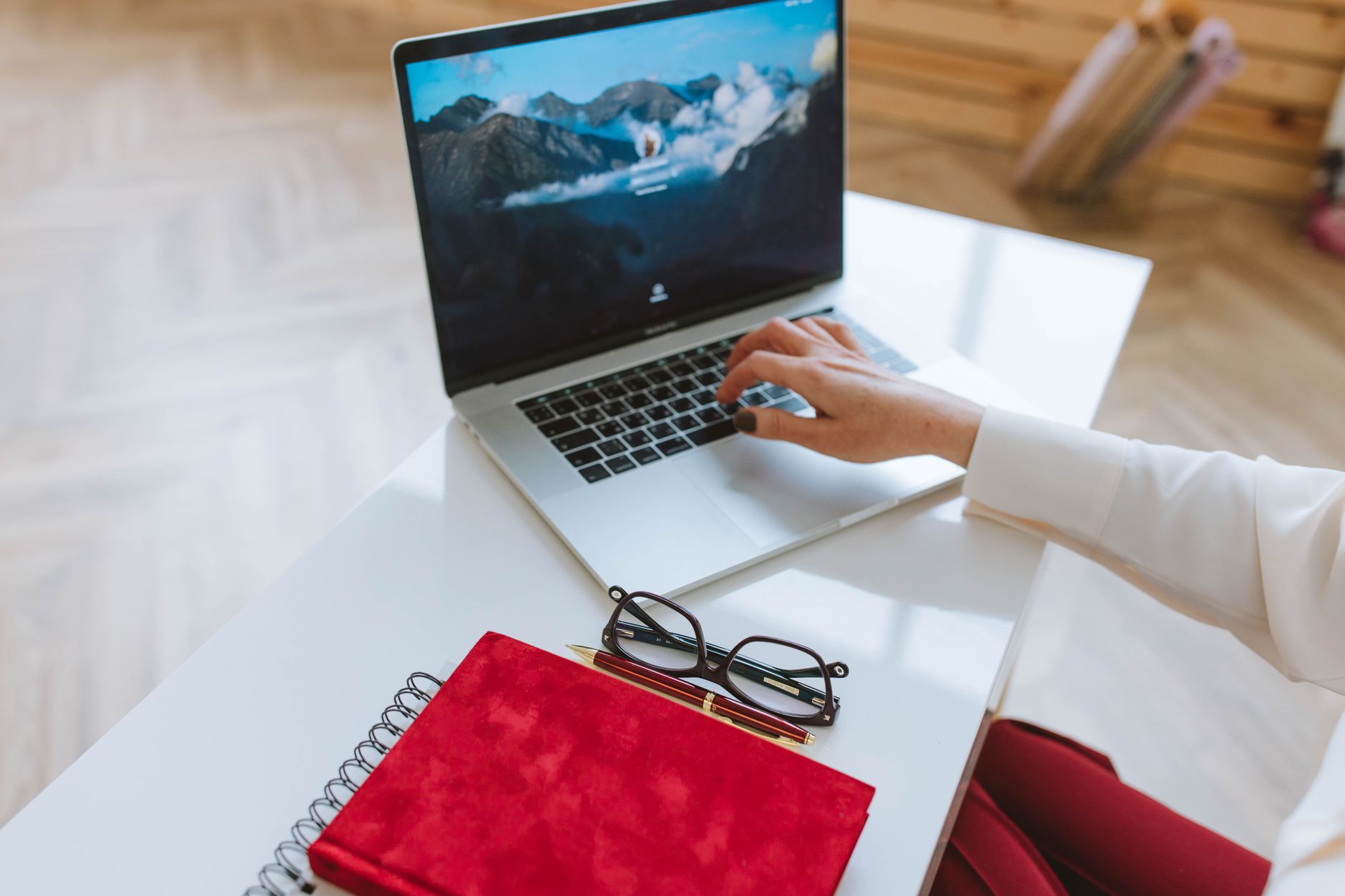Hands typing a new password on a laptop at a clean home desk with a notebook nearby.